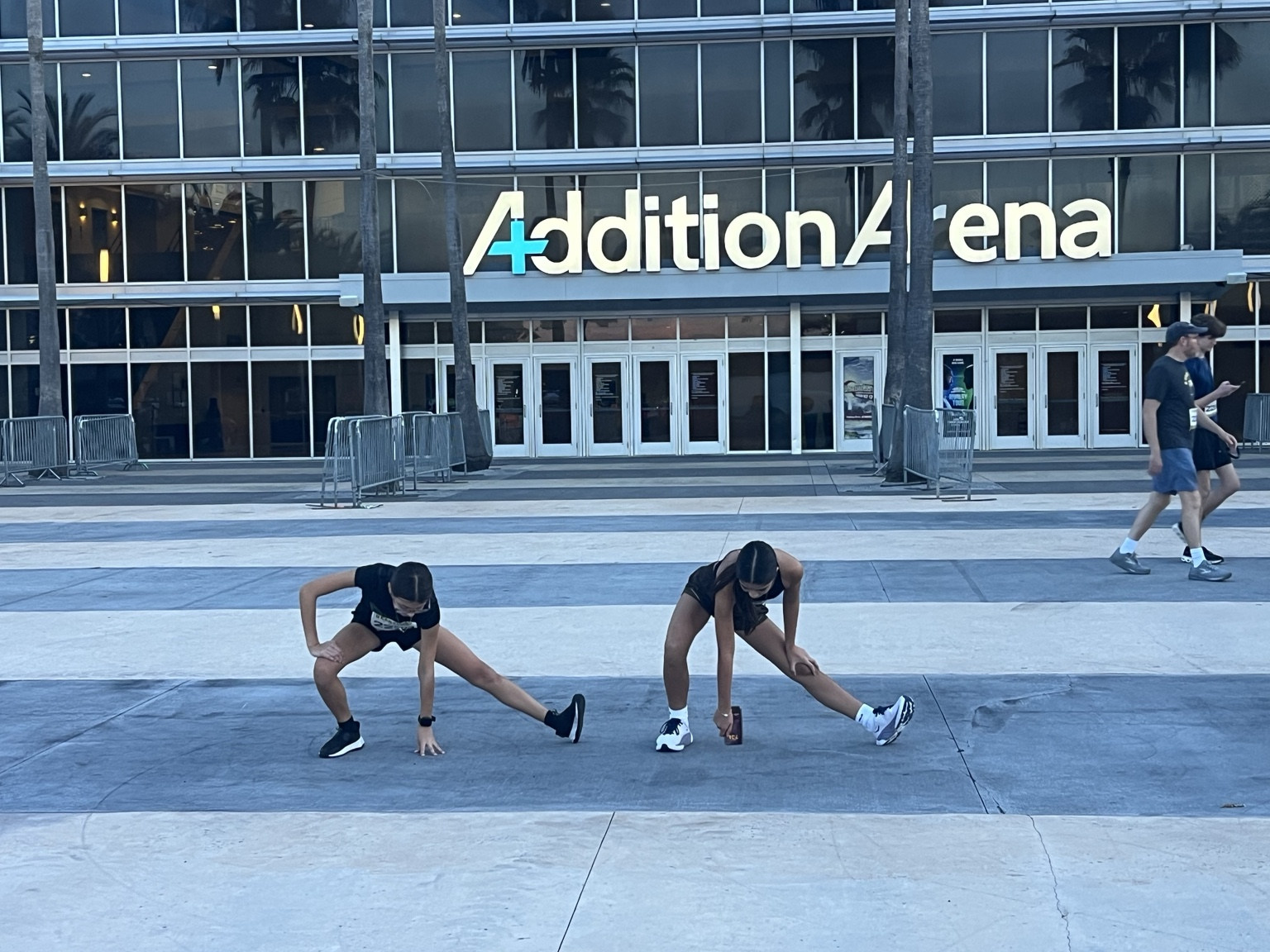 Two athletes stretching outside Addition Financial Arena