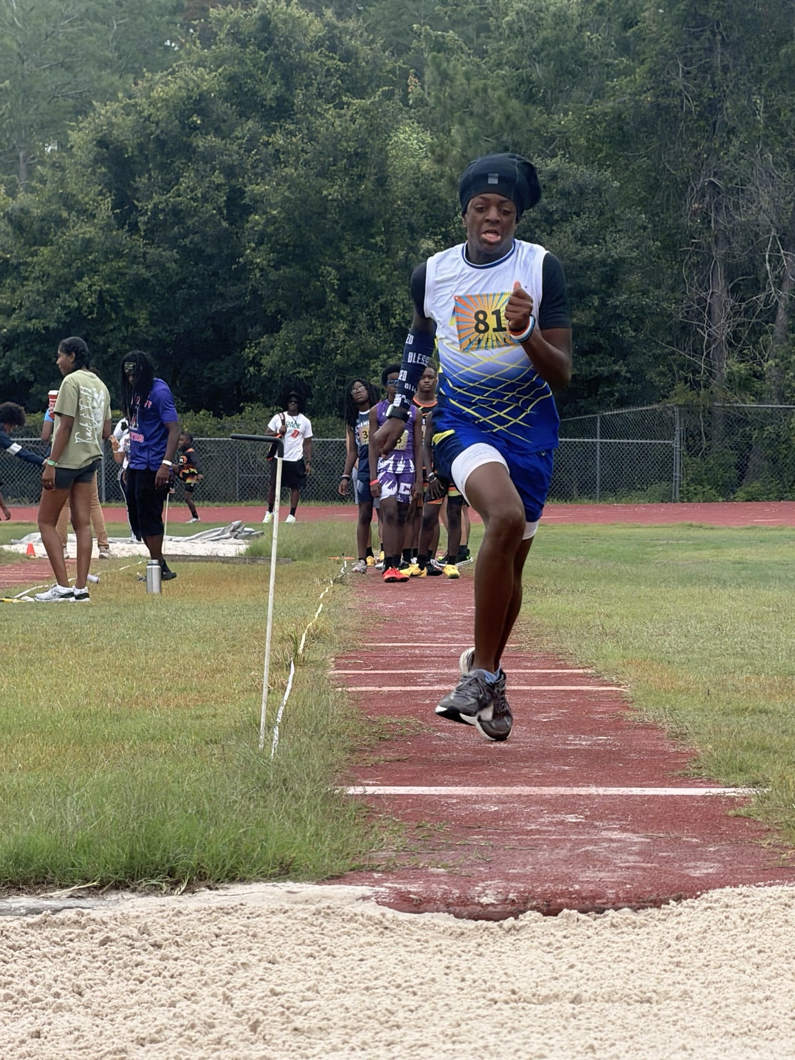 Youth athlete in blue uniform during long jump