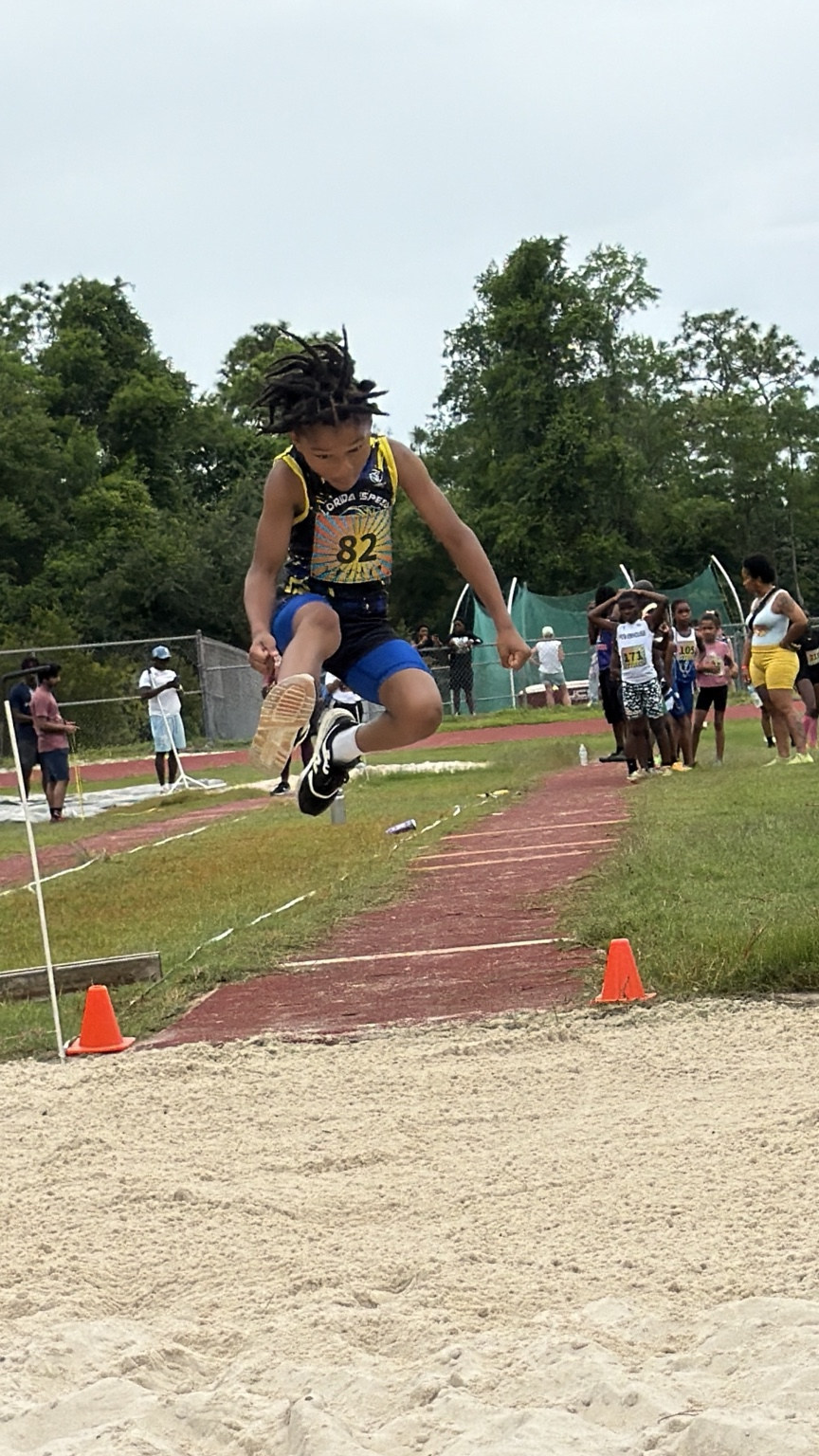 Young athlete in blue and yellow during long jump
