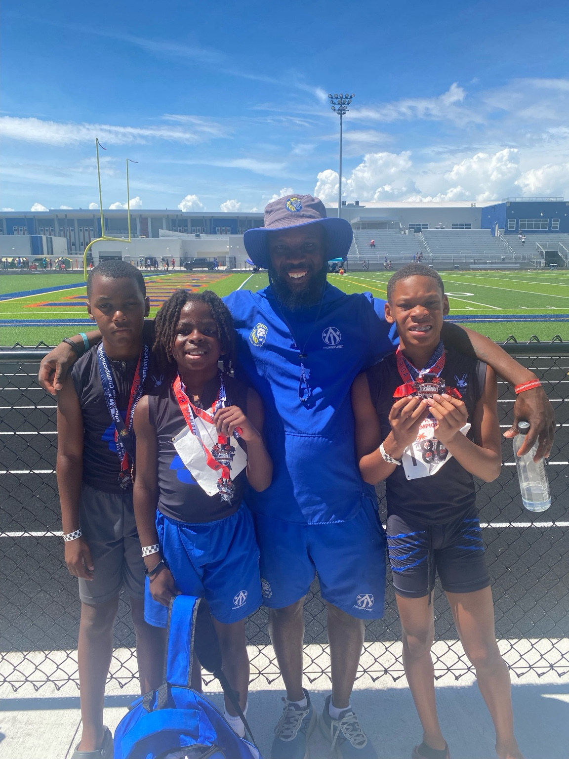 Coach and three youth athletes showing medals