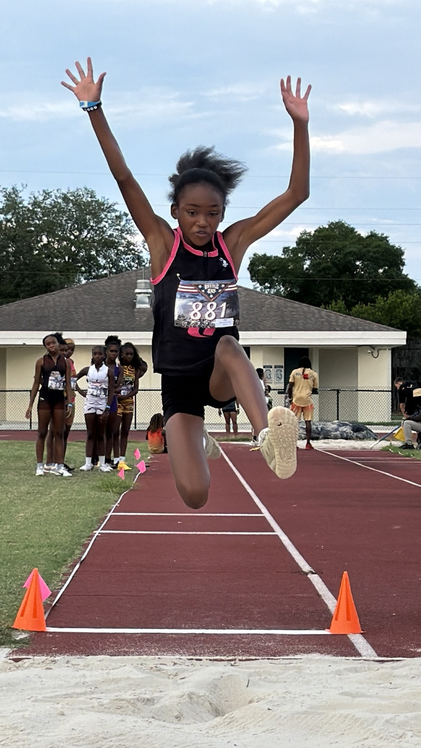 Young long jumper airborne over the runway
